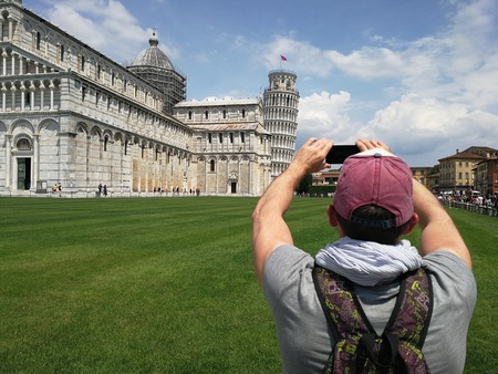 Stylish guy with a phone taking pictures of the Leaning Towerの写真素材