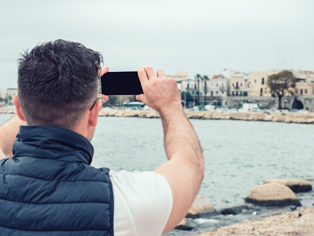 Stylish, happy man with a phone on the background of a seaの写真素材