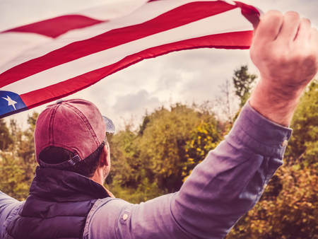 Attractive man in a baseball cap, holding a US flagの写真素材