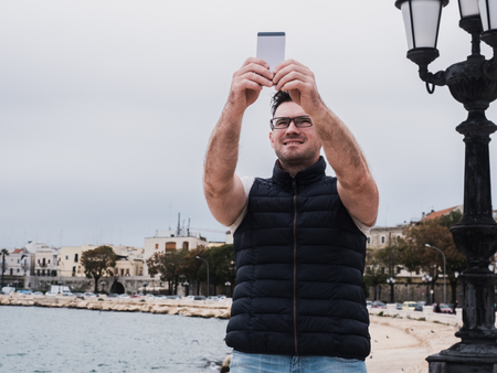 Stylish, happy man with a phone on the background of a sea
