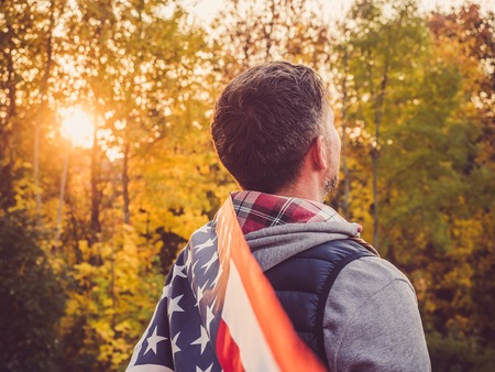 Attractive, stylish man holding a waving US Flagの写真素材