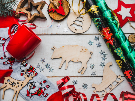 Happy New Year greeting card. Colorful Christmas decorations and toys, warm socks with Santa Claus, a red mug and ribbons on a white, wooden surface. Top view, close-up, flat layの写真素材