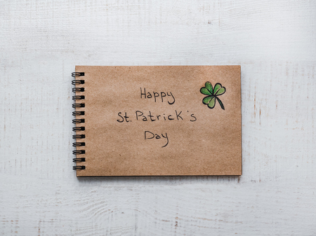St.Patrick 's Day. Beautiful card. Sketchbook with congratulatory inscription. Isolated background, closeup, top view, wooden surface. Congratulations for loved ones, relatives, friends and colleaguesの写真素材