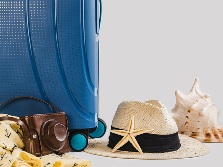 Stylish, blue suitcase, vintage camera and sun hat on a white, isolated background. Close-up. Preparing for the summer tripの写真素材