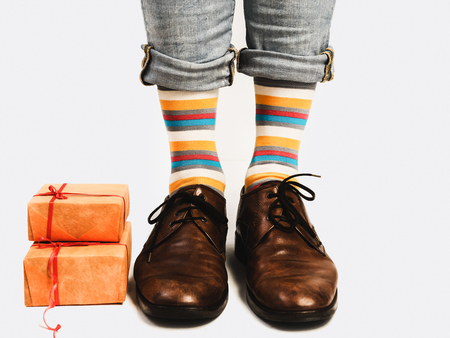 Office Manager in stylish shoes, blue pants, bright, colorful socks and boxes with gifts on a white, isolated background. Close-up. Lifestyle, fashion, fun, eleganceの写真素材