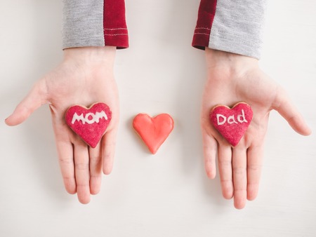 Hands of a younger daughter, beautiful glazed cookies and word MOM on a white, isolated background. Top view, close-up. Preparing for the holidaysの写真素材