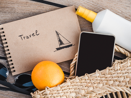 Ripe oranges, wicker basket, sunblock and sunglasses. Top view, close-up. Concept of leisure and...