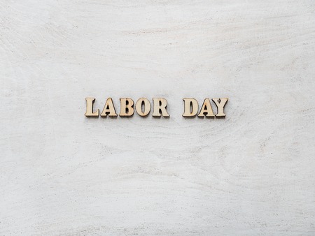 Wooden letters with a congratulatory inscription LABOR DAY. Close-up, top view, isolated. Concept of preparing for the holiday. Congratulations for loved ones, relatives, friends, colleaguesの写真素材
