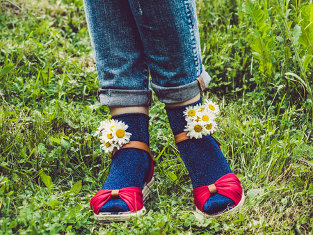 Women's legs, fashionable shoes, bright multi-colored socks on a background of green grass....