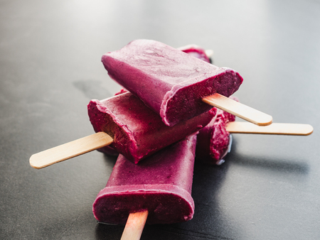 Bright, fruity red ice cream with wooden sticks on a black table. Close-up, top view. Tasty and healthy food conceptの写真素材