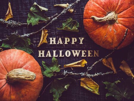 Letters of the alphabet in the form of the inscription Happy Halloween and ripe, bright pumpkins lying on a wooden surface. Close-up. Congratulations to loved ones, family, friends and colleagues