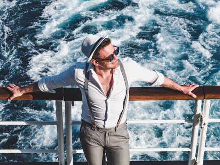 Smiling man on the empty deck of a cruise liner on the background of sea waves. Top view, close-up....
