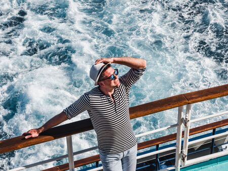 Smiling man on the empty deck of a cruise liner on the background of sea waves. Top view, close-up....