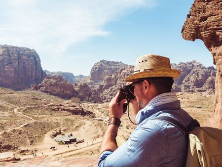Fashionable tourist with a vintage camera, photographing the main attraction of the city of Petra in...