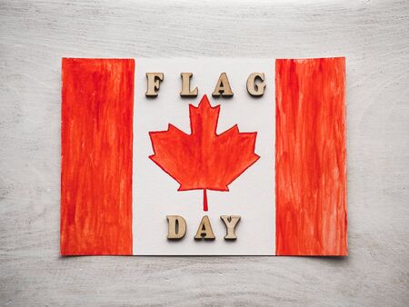 Beautiful drawing of the canadian flag and wooden letters of the alphabet. White isolated background, close-up, view from above. Congratulations for relatives, friends and colleaguesの写真素材