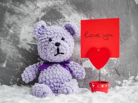 Bright plush toy, blooming red rose, white plaid and a note with a handwritten inscription. Studio photo. Close-up, indoorsの写真素材