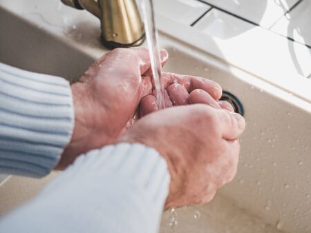 Men's hands and a bar of soap on a background of a vintage tap. Top view, closeup. Health Care and Prevention Conceptの写真素材