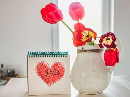 Beautiful card with a childish heart pattern and the word DAD. Close-up, side view. Concept of preparing for a family holiday. Congratulations to family, relatives, friends and colleaguesの写真素材