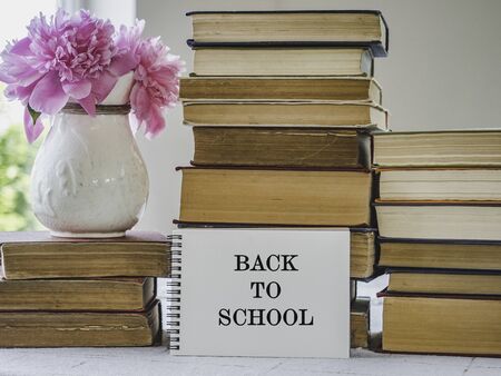 Stack of vintage books and a bouquet of beautiful flowers. Close-up, isolated background. Studio...