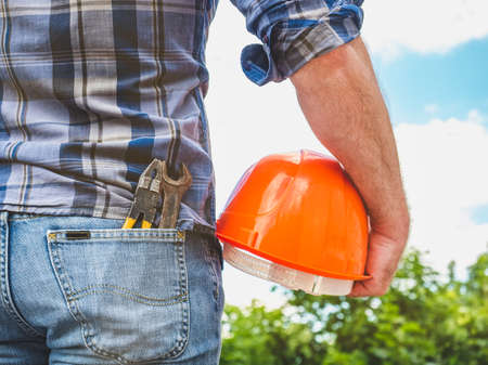 Man with tools holding a safety helmetの写真素材