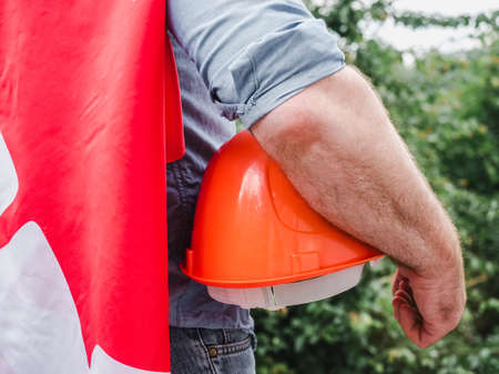 Handsome man with tools, holding an American Flag. View from the back, close-up. Concept of work and employmentの写真素材