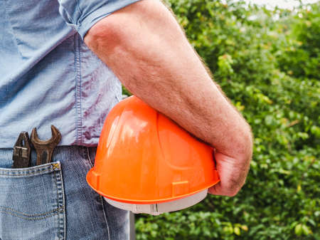 Man with tools, holding a safety helmet