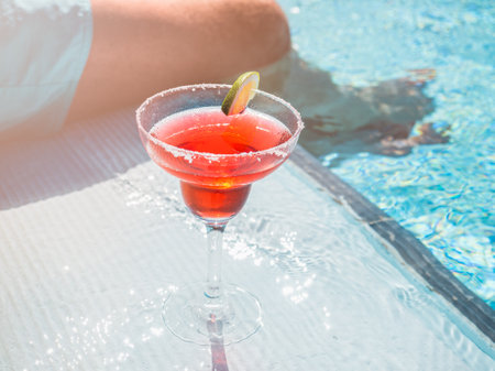 Beautiful glass with a refresh cocktail and an attractive man on the background of the swim pool....