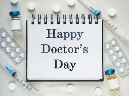 Happy Doctors Day. Syringes, injection vials and a notepad