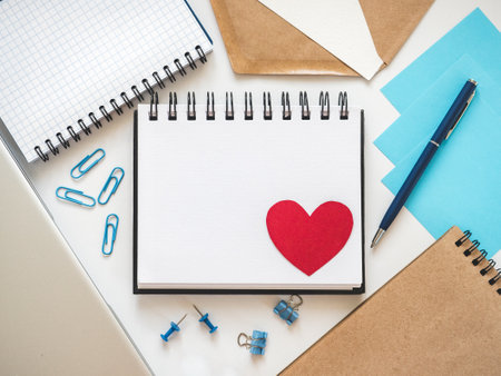 Blank notepad page and red heart drawing. Congratulatory inscriptions. Close-up, indoors. Studio...