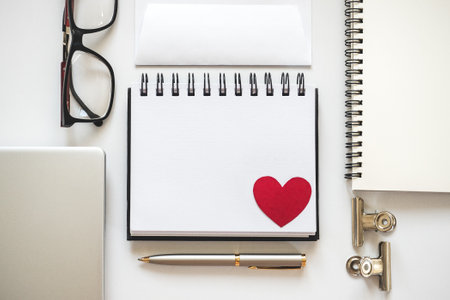 Blank notepad page and red heart drawing. Congratulatory inscriptions. Close-up, indoors. Studio shot, top view. Congratulations for family, relatives, loved ones, friends and colleaguesの写真素材