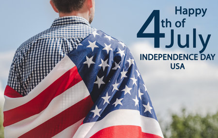 Happy Independence Day. Handsome man holding American Flag. Close-up, outdoors. Congratulations for family, loved ones, friends and colleagues. Concept of preparation for the national holidayの写真素材