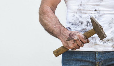 Handsome worker, hammer and dirty t-shirt. Labor day. Front view, close up, studio shot. Labor and employment conceptの写真素材
