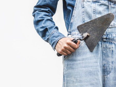 Cute woman, work clothes and masonry trowel. Labor day. Close-up, indoors. Studio shot. Front view, close-up. Labor and employment conceptの写真素材