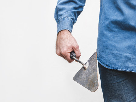 Handsome man, work clothes and masonry trowel. Labor day. Close-up, indoors. Studio shot. Front view. Labor and employment conceptの写真素材