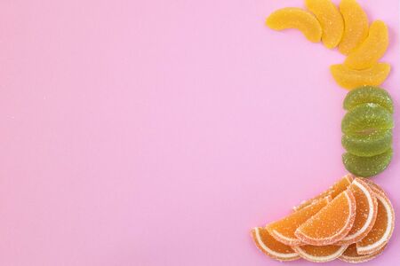 Multi-colored slices of fruit marmalade laid in the pink background.の写真素材