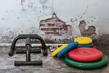 Professional dumbbells, multi-colored weight plates and push-up stops on a vintage background....