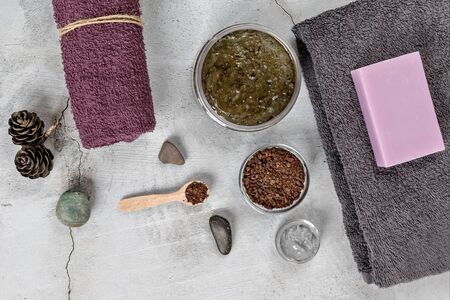 On a gray background are accessories for Spa self-care: body scrub, ground coffee, lavender soap, Terry towels for face and body.の写真素材