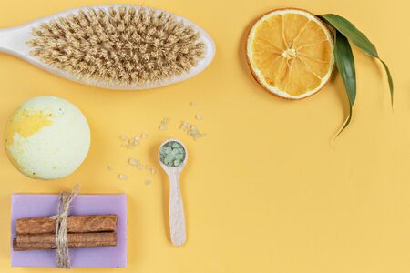 On an orange background are care products: a body wash, a bomb and sea salt for the bath, lavender soap. For aromatherapy: orange slices, cinnamon sticks. The concept of home Spa.の写真素材