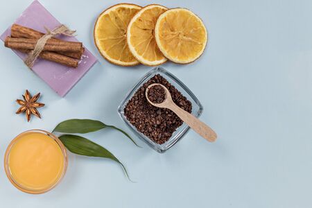 On a blue background are care products: lavender soap and mango cream for face and body after, coffee scrub. For aromatherapy: cinnamon sticks, anise star, sliced orange circles. Spa conceptの写真素材