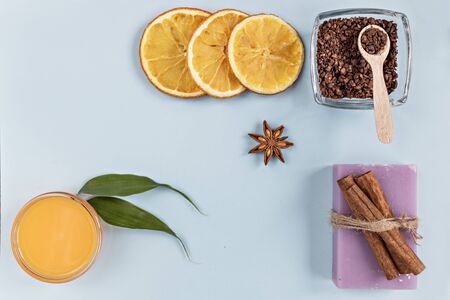 On a blue background are care products: lavender soap and mango cream for face and body after, coffee scrub. For aromatherapy: cinnamon sticks, anise star, sliced orange circles. Spa conceptの写真素材