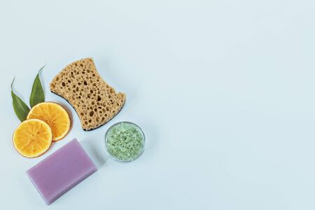 On a blue background - care products: lavender soap, natural sponge, sea bath salt. For aromatherapy: sliced orange. Home spa conceptの写真素材