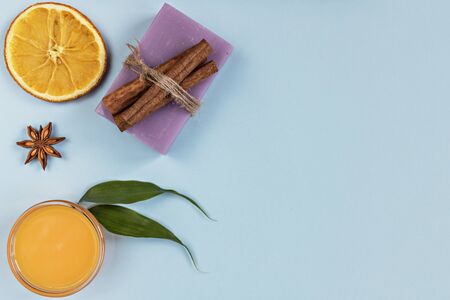 On a blue background are care products: lavender soap and mango cream for face and body after, coffee scrub. For aromatherapy: cinnamon sticks, anise star, sliced orange circles. Spa home conceptの写真素材
