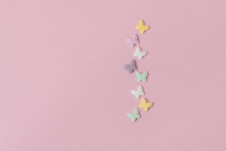 Pastry multicolored sprinkles-butterflies are laid out in the form of a chain on a pink background. Decoration of confectionery products.の写真素材