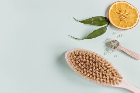 On an blue background are care products: a sea salt for the bath and body brush. For aromatherapy: orange slices. The concept of home Spa.の写真素材