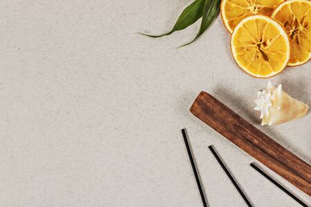 Incense sticks with a stand, sliced orange circles in a wooden bowl on a gray background. Also a seashell.Aromatherapy. The concept of home Spa.の写真素材