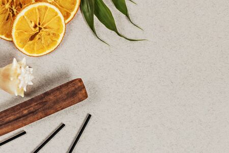 Incense sticks with a stand, sliced orange circles in a wooden bowl on a gray background. Also a seashell.Aromatherapy. The concept of home Spa.の写真素材