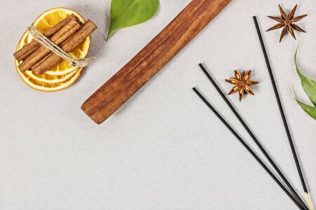 Incense sticks with stand, sliced in orange circles in a wooden bowl and anise star, cinnamon sticks on a gray background.Candle in the form of a flower and a shell.Aromatherapy. Home spa conceptの写真素材