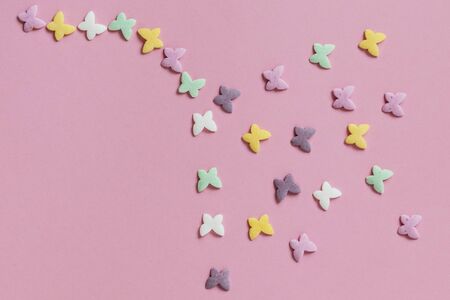 Pastry multicolored sprinkles-butterflies are laid out in the form of a flying snake on a pink background. Decoration of confectionery productsの写真素材