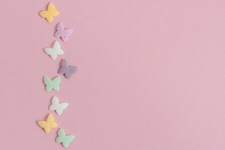Pastry multicolored sprinkles-butterflies are laid out in the form of a chain on a pink background. Decoration of confectionery products.の写真素材