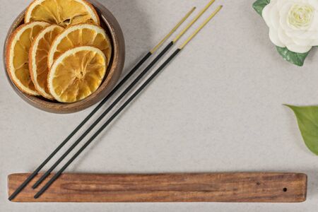 Incense sticks with stand, sliced in orange circles in a wooden bowl and anise star, cinnamon sticks on a gray background.Candle in the form of a flower and a shell.Aromatherapy. Home spa concept.の写真素材